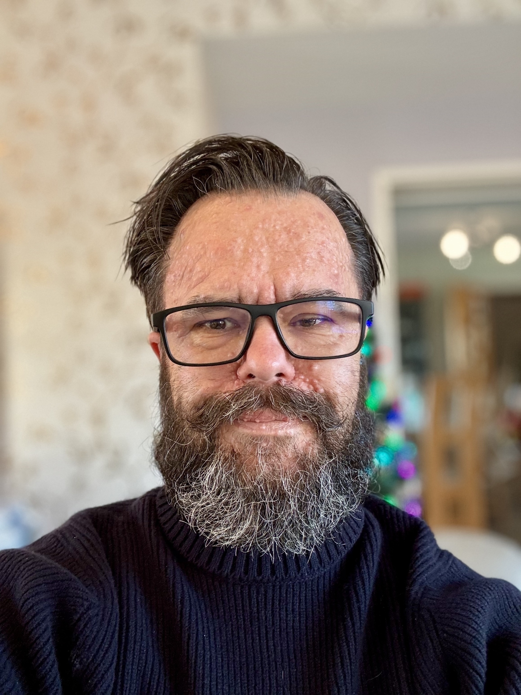 A smug faced bearded man shows off his new merino wool polo neck jumper. 